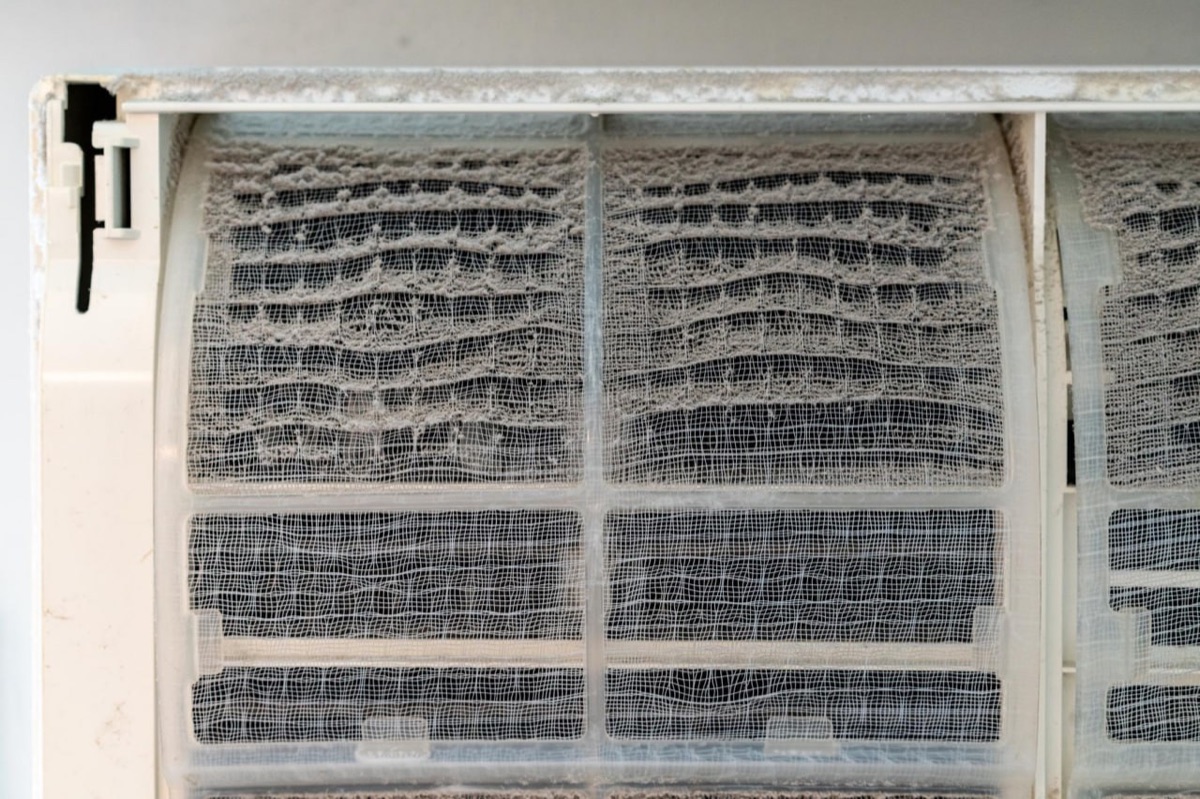 A ductless mini-split filter screen caked with grey dust and lint after a year without rinsing